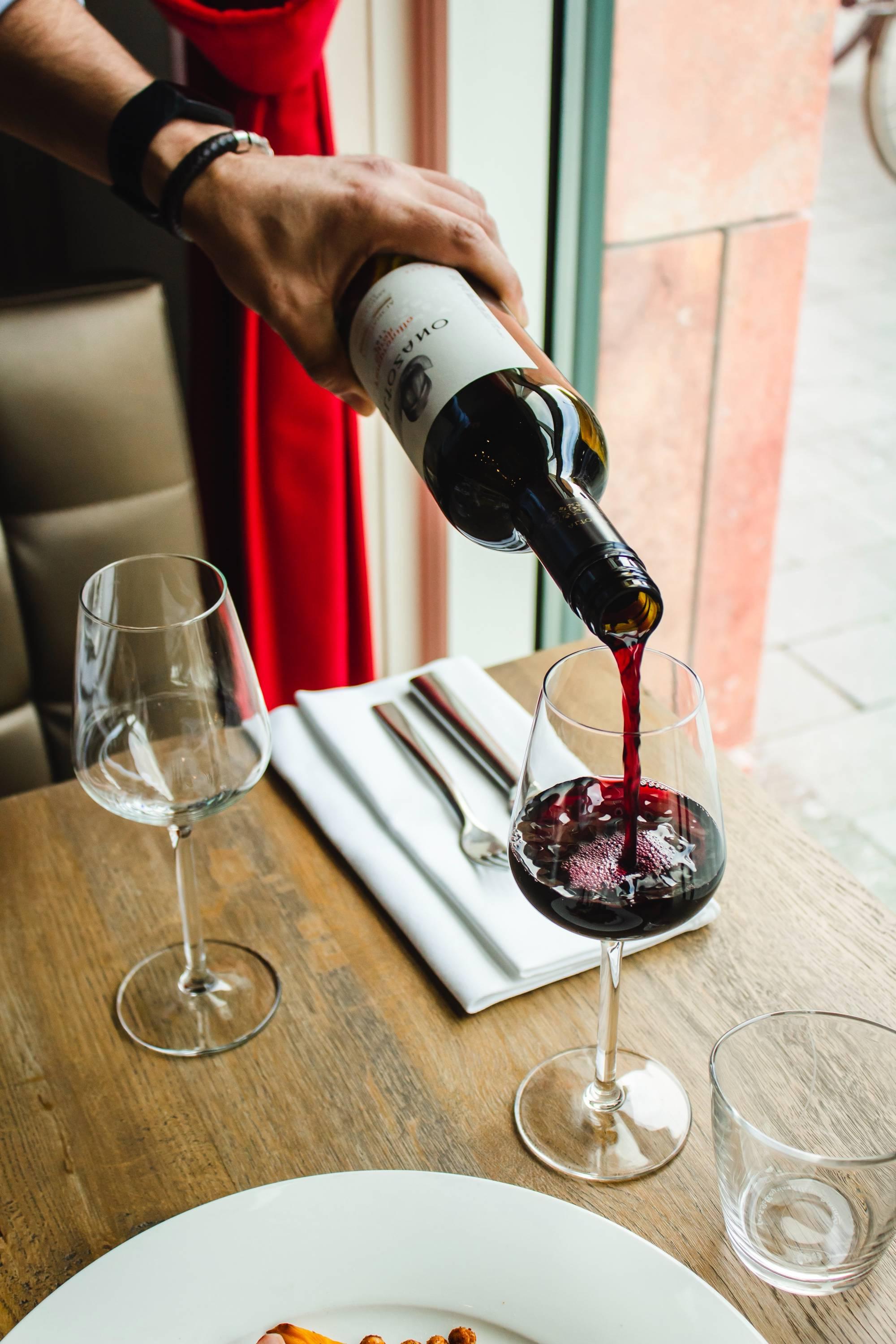 Red wine being poured into a wine glass at a restaurant